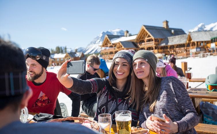 People enjoying a sunny day on Lake Louise ski resort with food and drinks 