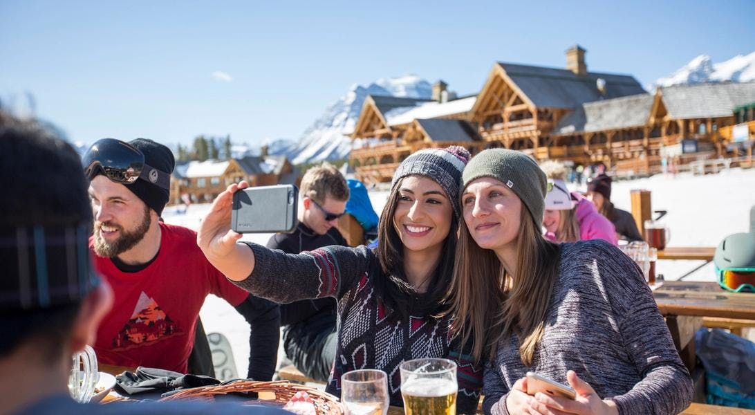 People enjoying a sunny spring day on Lake Louise Ski Resort with food and drinks. 