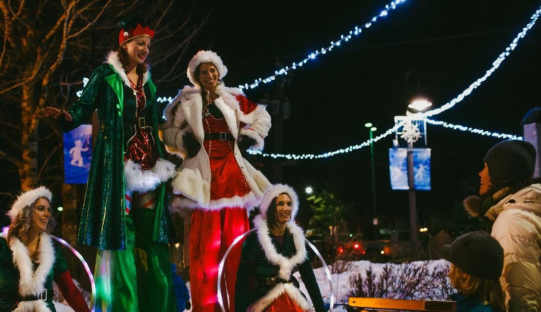 A family watches christmas themed stilt walkers in Banff for the Santa Claus Celebration of Lights